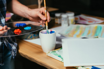 Fototapeta na wymiar Artist palette colors. Paintbrush in hands. Man at workplace. Gaining inspiration creating artwork enjoying hobby leisure.