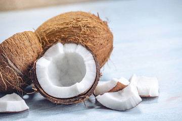 Open coconut with white pulp on blue wooden background. Organic healthy vegan product widely used in cosmetics