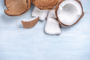 Open coconut with white pulp on blue wooden background. Organic dietary vegan product widely used in cosmetics