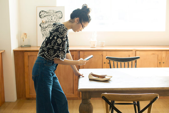 スマホで靴の写真を撮る20代女性