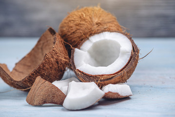 Open coconut with white pulp on blue wooden background. Organic healthy dietary product widely used...