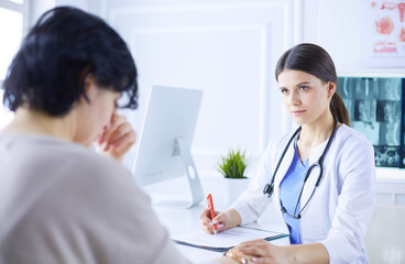 Female doctor calming down a patient at a hospital consulting room, holding her hand