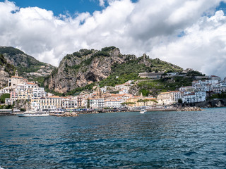 Fototapeta na wymiar Positano, Salerno, Campania, Italy, Europe: view of Amalfi from the sea on a boat entering the port on the Amalfi Coast. Wake of a ship with a marine village in the background