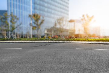 empty asphalt road near glass office building.