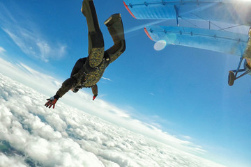 Skidiver in military uniform jumping out of the plane