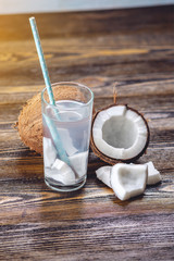 Coconut water in the composition with white flesh on wooden background. Organic product widely used in cosmetology