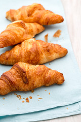 Tasty buttery croissants on old wooden table.