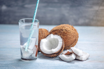 Coconut water in the composition with white flesh on blue wooden background. Organic product widely used in cosmetology
