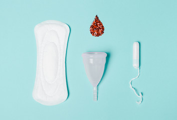 Tampon, Pad, menstrual cup with a drop of blood on a blue background. The view is flat. Concept of...