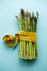 Raw asparagus and measuring type isolated on a blue background