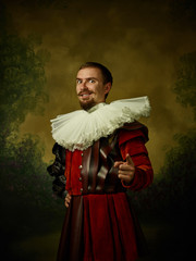 Young man as a medieval knight on dark studio background. Portrait in low key of male model in...