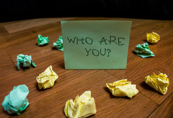 Handwriting text Who Are You Question. Conceptual photo asking about someone identity or demonstratingal information Colored small wrinkled paper balls standing square note lying wooden table