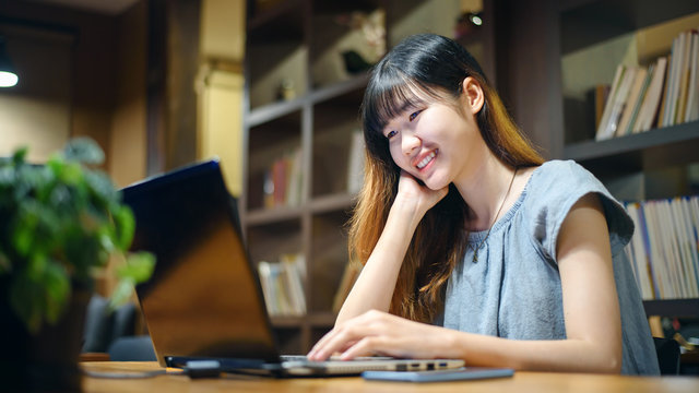 Happy Beautiful Asian Student woman working on  laptop in  modern library  room