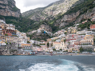 Fototapeta na wymiar Positano, Salerno, Campania, Italy, Europe - may 19 2019: view of Positano from the sea on a boat leaving the port on Amalfi Coast. Wake of a ship with a marine village in the background
