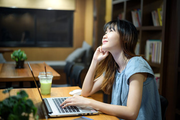 Happy Beautiful Asian Student woman working on  laptop in  modern library  room