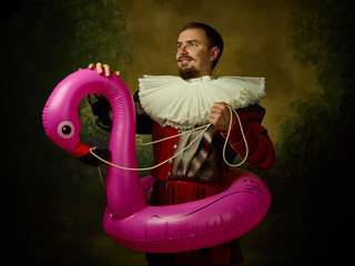 Young man as a medieval knight on dark background. Portrait in low key of male model in retro...