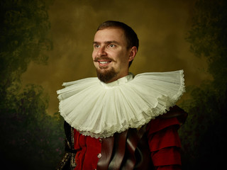 Young man as a medieval knight on dark studio background. Portrait in low key of male model in...