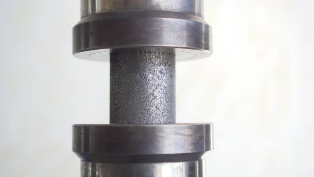 In the white laboratory, the heavy press puts pressure on the graphite cylinder
