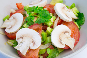 fresh vegetable salad tomatoes avocado vegan raw food with raw champignons, mushroom raw vegetables with olive oil