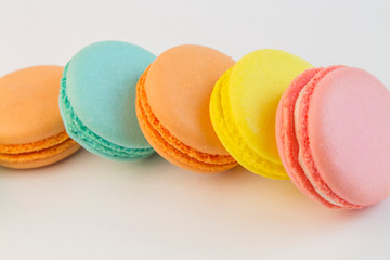 French pastry cookies cupcake macarons close-up. Macaroons multi color on a white background, yellow pink blue macaronis