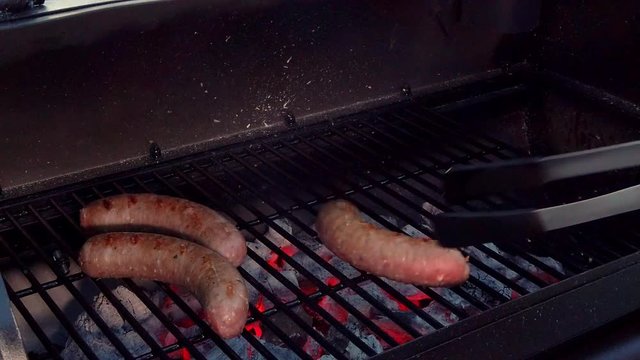 Putting Sausages on the grill to cook them on the BBQ.