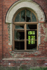 Obraz premium broken window in an abandoned house, broken glass, red brick, forgotten residence