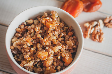 closeip top view on A bowl of porridge with wallnuts and dry apricot on the white wodden table. Orthodox chistmas kutya.  Orthodox chistmas celebration dish.