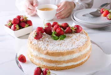 Woman drinking green tea and eating tasty sponge cake with strawberries.Tea party