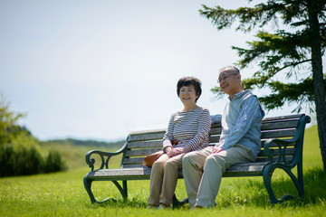 ベンチに座り微笑むシニア夫婦