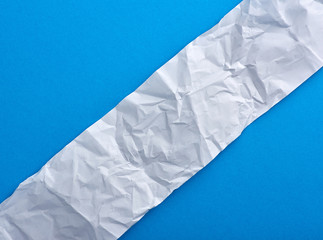Obraz premium strip of crumpled blank white paper on a blue background