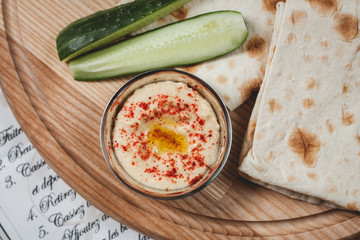 Top view  hummus bowl serving with flat bread and cucumber slices. Middle east and Mediterranean chickpea dip.  