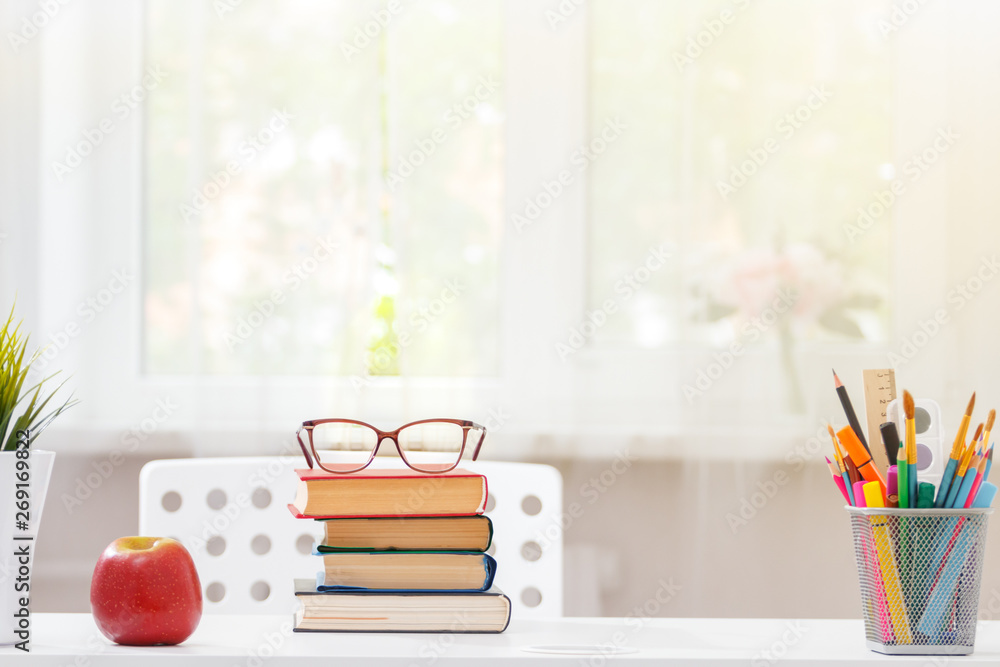Poster close-up of a white schoolchild desktop. on the table is a stack of books. light from the window. bl