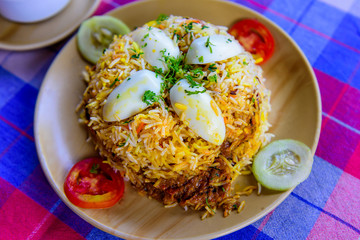 Egg Biryani - Basmati rice cooked with masala, eggs and spices, overhead view, close up. Egg Pilaf or Pulao served with vegetables and yogurt.