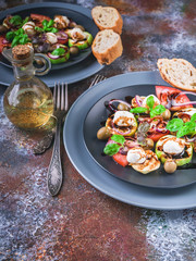 Italian salad with grilled vegetables, mozzarella cheese, olives, red onion, basil and balsamic sauce on a rust background. Mediterranean Kitchen. Close-up