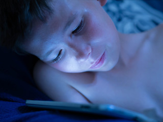 Child looks at a Tablet PC during the night