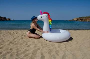 Summer and vacation. Woman kissing inflatable unicorn pool float in beach