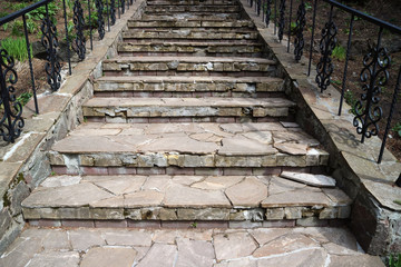 A staircase of stone leading up to the shed with rails in black steel.