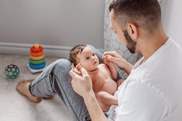 Young Caucasian bearded father holding newborn baby on laps knees. Male man parent rocking talking to child daughter son. Authentic lifestyle documentary moment. Single dad family life. - 269171843