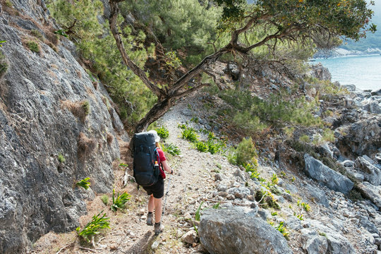 A woman with a backpack is hiking along the coastline on the greek island Crete