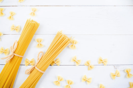 bunch of long dry spaghetti on a white wooden table. Italian cuisine concept, food ingredients. Flat lay. Top view
