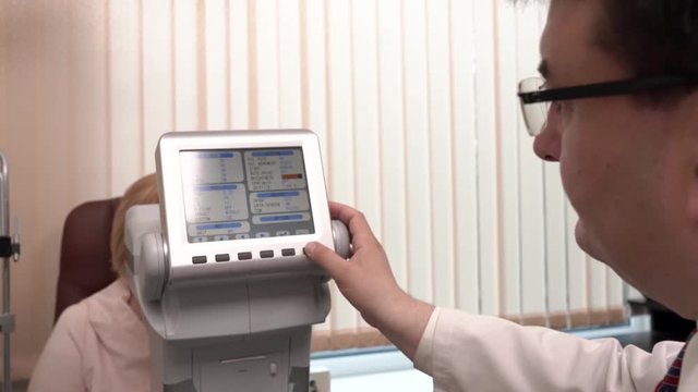 A front view of a professional ophthalmologist performing eyesight check-up using automated refractor. Vision testing for senior people.