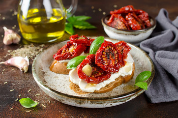 Bruschetta with olive oil, sundried tomatoes, cottage cheese and fresh basil - obrazy, fototapety, plakaty