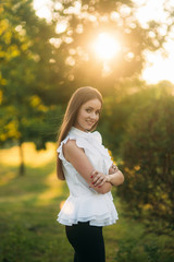 Beautiful female in the park. Attractive woman in white shirt outside