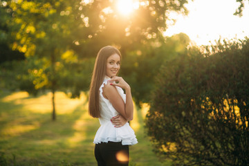 Beautiful female in the park. Attractive woman in white shirt outside