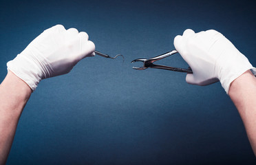 Hands in gloves holding surgery dental tools on dark blue background