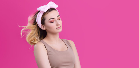Obraz na płótnie Canvas portrait of a beautiful girl woman in a headband for make up on pink studio background, concept of beauty, advertising cosmetics, body care