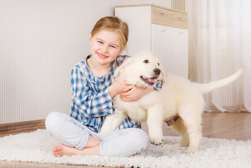 Smiling little girl hugging cute fluffy retriever puppy at home