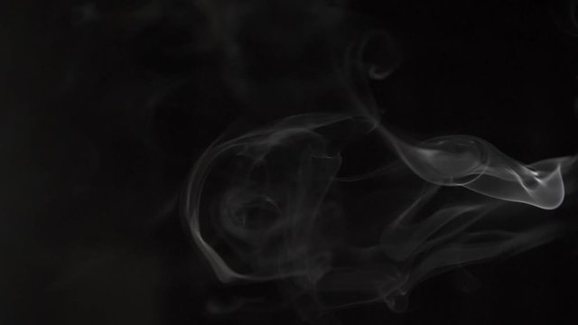 slow motion puffs of white smoke moving from right to left on a black background