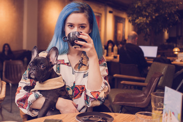 Young hipster woman in cafe with dog drinking coffee 