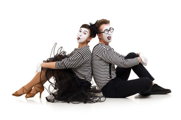Smiling mimes in striped shirts. Man and woman dressed as actors of pantomime theater sitting on...